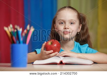 Portrait Of Happy Pretty Girl Holding A Red Apple In The Classroom