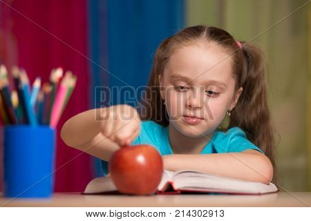 Portrait Of Happy Pretty Girl Holding A Red Apple In The Classroom