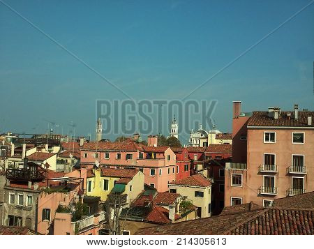 Roofs of city. Top view on old block with classic brick buildings and houses. Roofs are covered by red tiles and walls are painted by bright colors. Deep blue sky is above. Architecture background