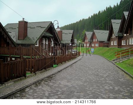 Wooden cottages are at mountain resort near forest under blue sky