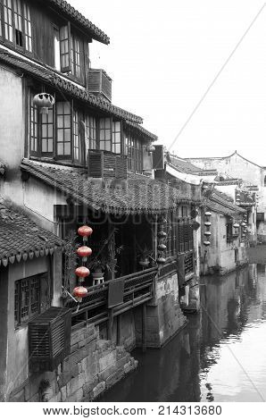 A black and white picture of the Chinese architecture and buildings lining the water canals to Xitang water town in Zhejiang Province China.