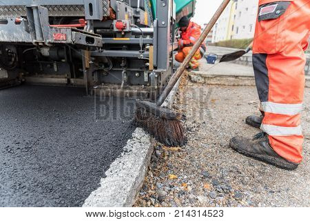 Workers at asphalting works of a sidewalk - close-up
