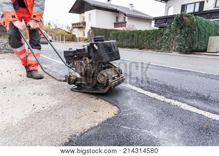 Hard worker at asphalting works with a shaker - closeup