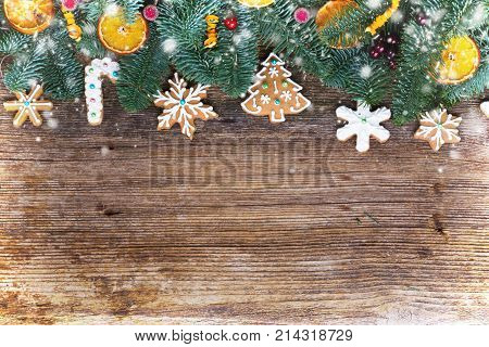 christmas gingerbread iced cookies with fir tree flat lay border, copy space on wooden background with snow