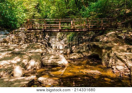 Wooden bridge over the Agura river in the Agura gorge in sunny summer day Sochi Russia