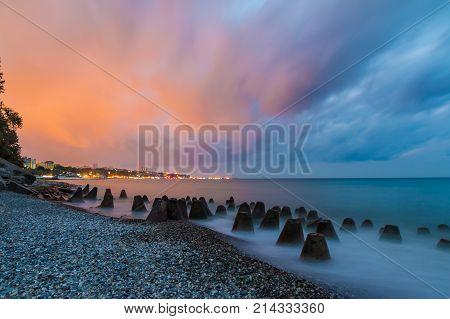 Long exposure photo of the concrete conical boulders lying in the sea on the background of coastline of Sochi at dawn Russia