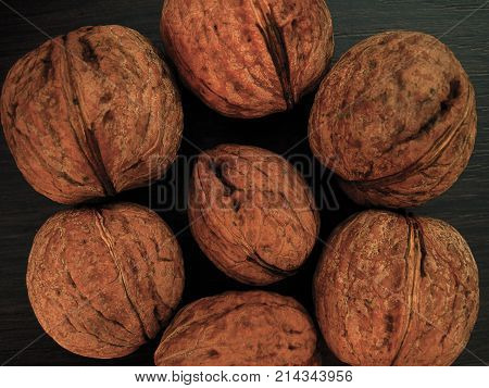 Walnuts on a table in contrast colors brown, dark and light. Harvest of autumn background or texture for fall theme. Flat layout view. Raw nuts with unbroken nutshell from a garden