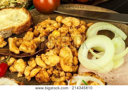Heap of domestic salty fried pork greaves. Fatty junk food. Pork greaves on the kitchen board