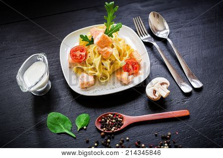 Pasta with salmon on dark background. Flat lay, top view. Restaurant, food
