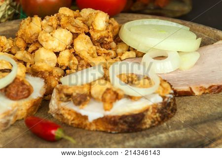 Heap of domestic salty fried pork greaves. Fatty junk food. Pork greaves on the kitchen board