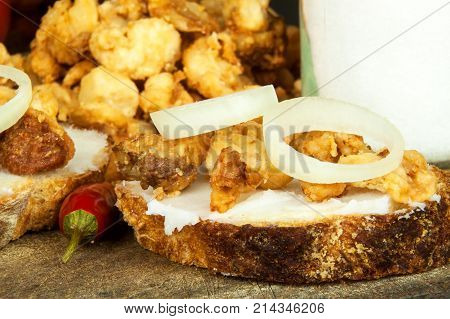 Heap of domestic salty fried pork greaves. Fatty junk food. Pork greaves on the kitchen board