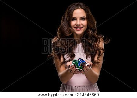 Female Poker player with paint black nails hold her poker chips to make a bet. Gambling and casino business concept. Studio shot on a black background. Casino