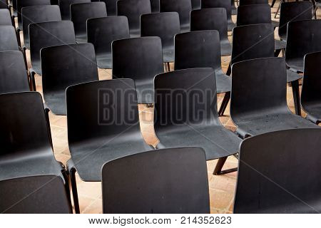 lines of black chairs in an empty auditorium