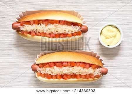 Chilean Completo Clasico (classical) or Completo Aleman (German) traditional hot dog sandwiches made of bread sausage tomato cubes and sauerkraut mayonnaise in small bowl on the side photographed overhead with natural light