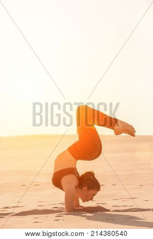 Fitness yoga woman stretching on sand. Fit female athlete doing yoga pose before running training outside in amazing landscape.