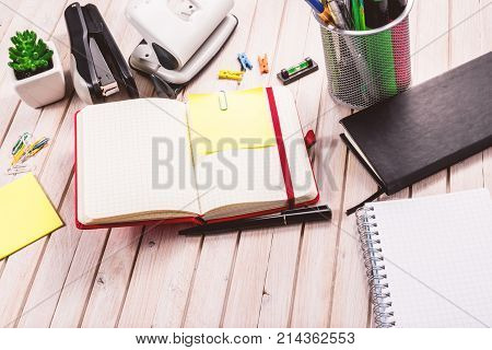 Top view workspace mockup on wooden background with blank notebook with copy space, pen, tacker, punch, clips and accessories. Overhead view. Flat lay, top view