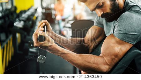 Strong ripped man training bicepses in gym