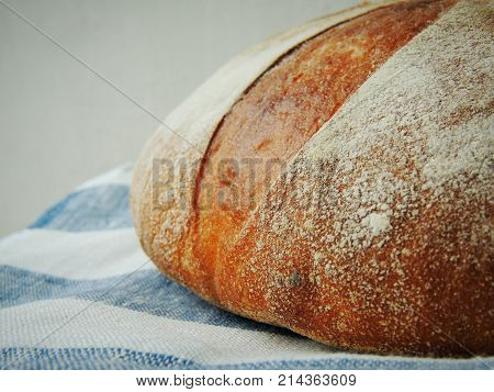 Fresh loaf of bread on striped white blue linen towel.