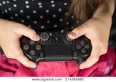 UFA RUSSIA - NOVEMBER 12 2017: Hand girl playing Sony Dualshock 4 controller for PlayStation 4 pro. Sony PlayStation 4 pro game console of the eighth generation.