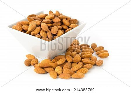 Heap of shelled almond kernels in white bowl over white background