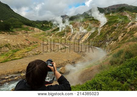 Tourist takes a picture of the famous Valley of Geysers. Kronotsky Nature Reserve on Kamchatka Peninsula.