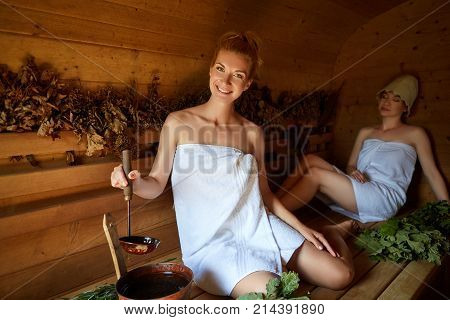 two beautiful young women in towels realxing in wooden sauna. inside shot with natural light.