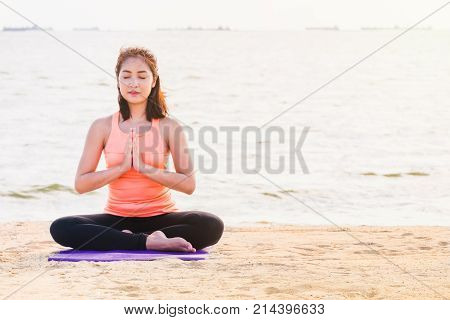 Asian woman close eyes and doing Hand namaste yoga pose and meditates on sand at coastline beach Calm and relax conceptwellness and healthy lifestyle