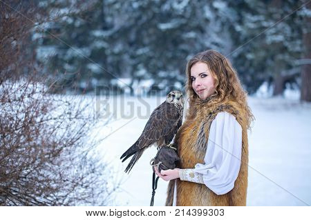 Beautiful red-haired woman with a falcon in winter