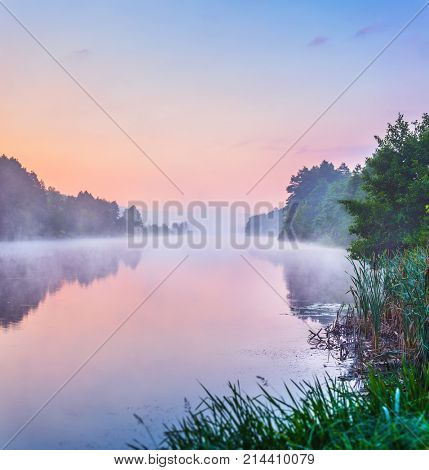 Landscape with sunrise and mist over river matutinal picturesque morning sky clouds in water sunbeam forest.