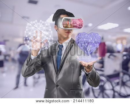 Asian Man wearing virtual reality in action hand holding the line of hearth shape and brain which can see Chemical Laboratory over photo blurred of hospital background VR technology concept