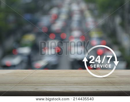 24 hours service icon on wooden table over blur of rush hour with cars and road Full time service concept