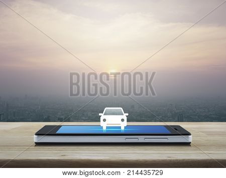 Taxi car flat icon on modern smart phone screen on wooden table over city tower at sunset vintage style Business transportation service concept