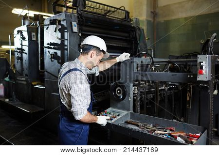 Factory master pressing button on panel of industrial machine during work