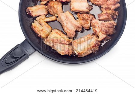 Top view of fragment of the frying pan with fried pork ribs on a white background