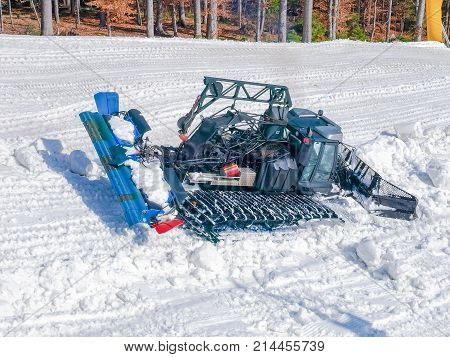 Top view of the snow groomer which prepare ski piste beside of the forest on ski resort in Carpathians