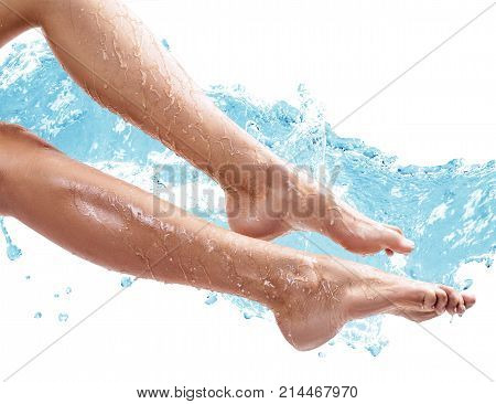 Sensual woman's legs in clean water splashes isolated on white background.