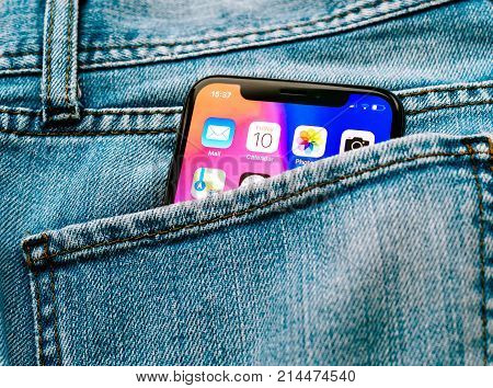 PARIS FRANCE - NOV 10 2017: New Apple iPhone X smartphone telephone mobile in pocket of fashion denim jeans pants trousers with home screen apps