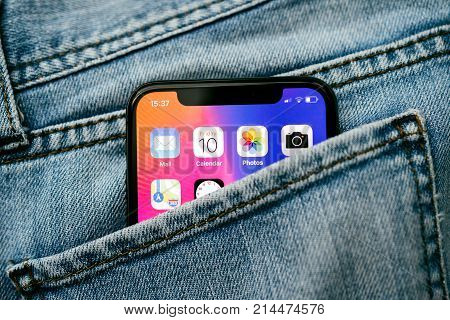 PARIS FRANCE - NOV 10 2017: New Apple iPhone X smartphone telephone mobile in pocket of fashion denim jeans pants trousers with home screen apps