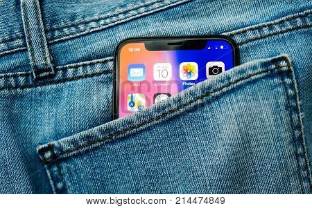 PARIS FRANCE - NOV 10 2017: New Apple iPhone X smartphone telephone mobile in pocket of fashion denim jeans pants trousers with home screen apps