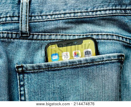 PARIS FRANCE - NOV 10 2017: New Apple iPhone X smartphone telephone mobile in pocket of fashion denim jeans pants trousers with home screen apps
