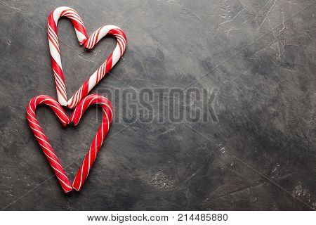 Peppermint Candy Canes In Heart Shapes On Black Concrete Background. Christmas Background. Top View