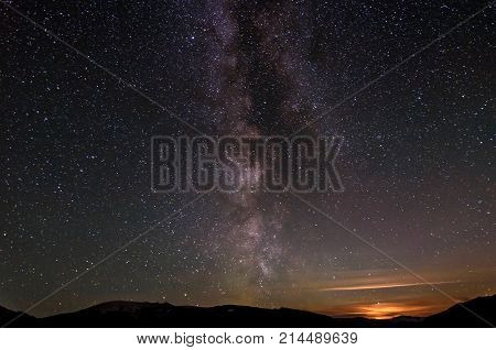 Beautiful panorama of the night starry sky with the Milky Way galaxy above the mountains stars and moonset
