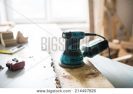 Angle grinder in carpenter workroom. Electric tool and tape measurer on the table.