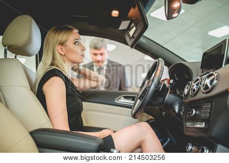Happy woman bying new electro car.Happy woman bying new electro car. Young pretty woman seating on front seat of the car.