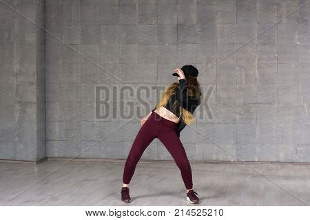 Young girl dancing contemporary dance. Young slim girl performing modern dance on grey studio background.