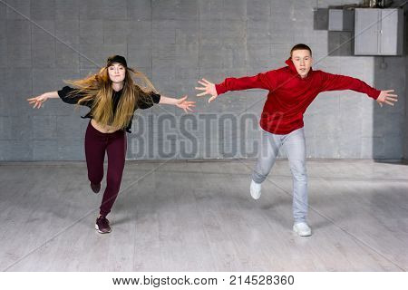Guy and girl in dance movement. Modern style young dancers performing hip-hop dance on studio background. Teenagers skill and talent of modern dance.