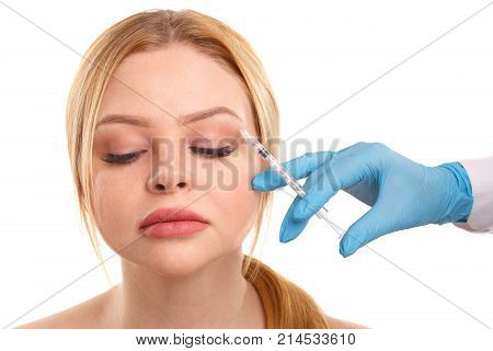 Introduction of injection into the eyebrow area of a young beautiful woman. Isolated on white background.