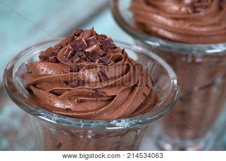 Dark chocolate mousse dessert served in glass bowl close up. Vintage green table background.