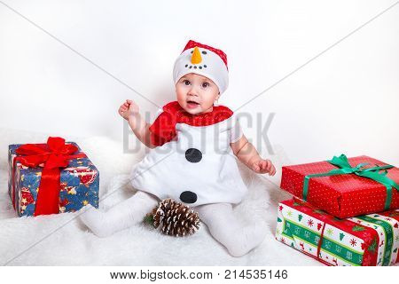 happy baby in snowman costume with christmas present gift boxs .Amazed attractive baby girl in Christmas costume sitting