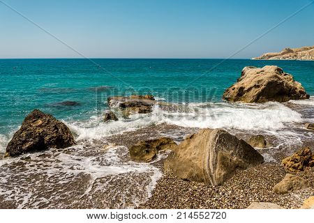 Waves entering Pissouri pebble beach through large rocks in the water Limassol district Cyprus